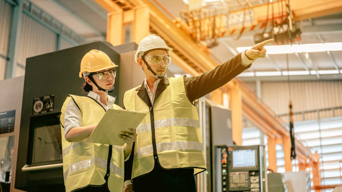 Industrial engineers in hard hats discuss new project while using blue print in industry manufacturing factory.Engineer and Architect concept.