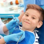 Dentist examining little boy's teeth in clinic