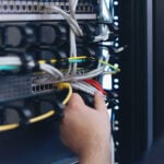 An Expert Engineer in datacenter server room connecting cables in server cabinet in network server room.